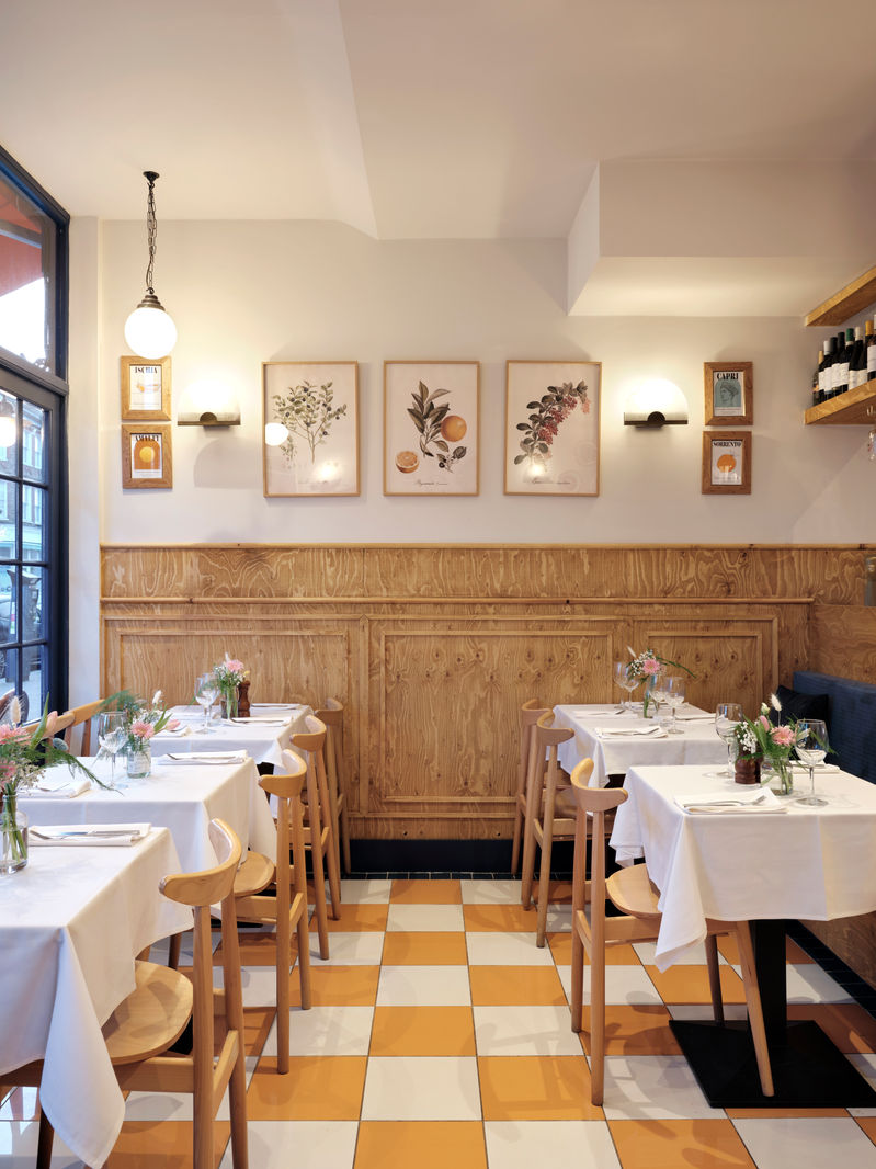 Dining room with wood panelling, botanical prints and white tablecloths